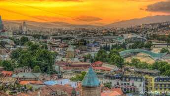 Stadtbild von Tiflis mit Hochhäusern unter orangefarbenem Himmel